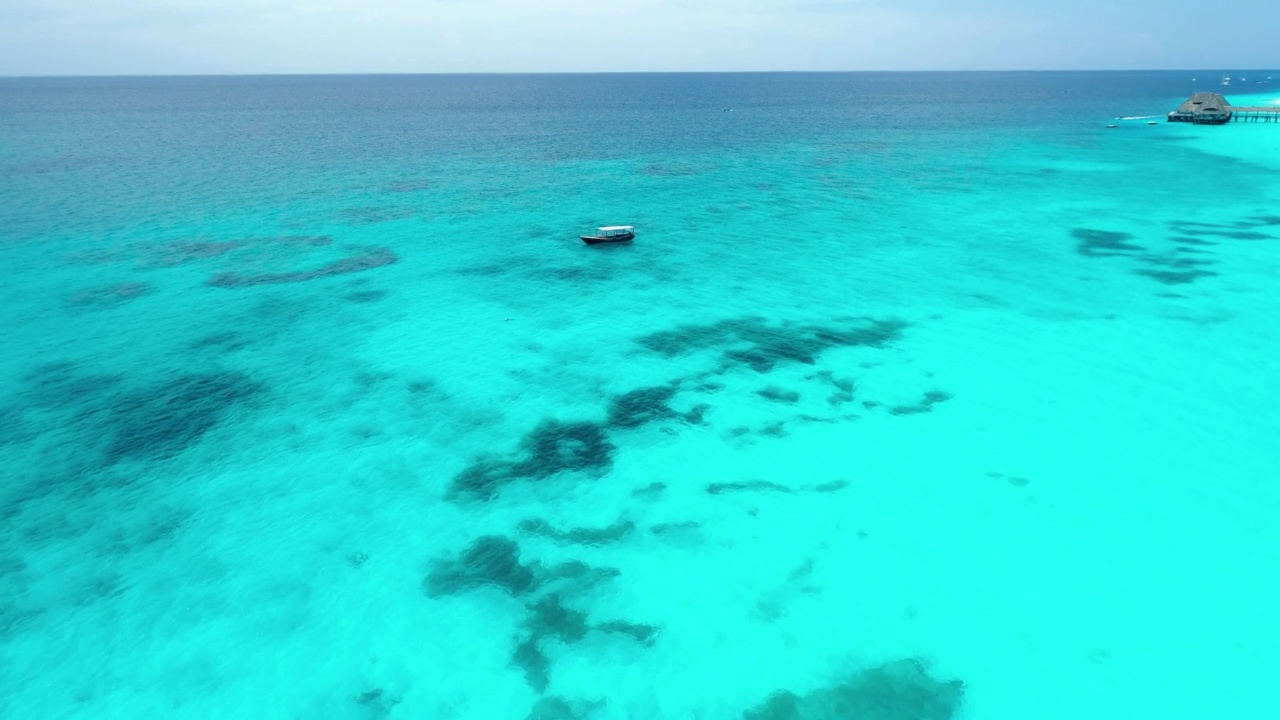 在晴朗的夏日里，渔船在湛蓝的海水里的鸟瞰图。从船上的无人机俯视，沙滩。非洲桑给巴尔的印度洋。风景与摩托艇，清澈的大海视频素材