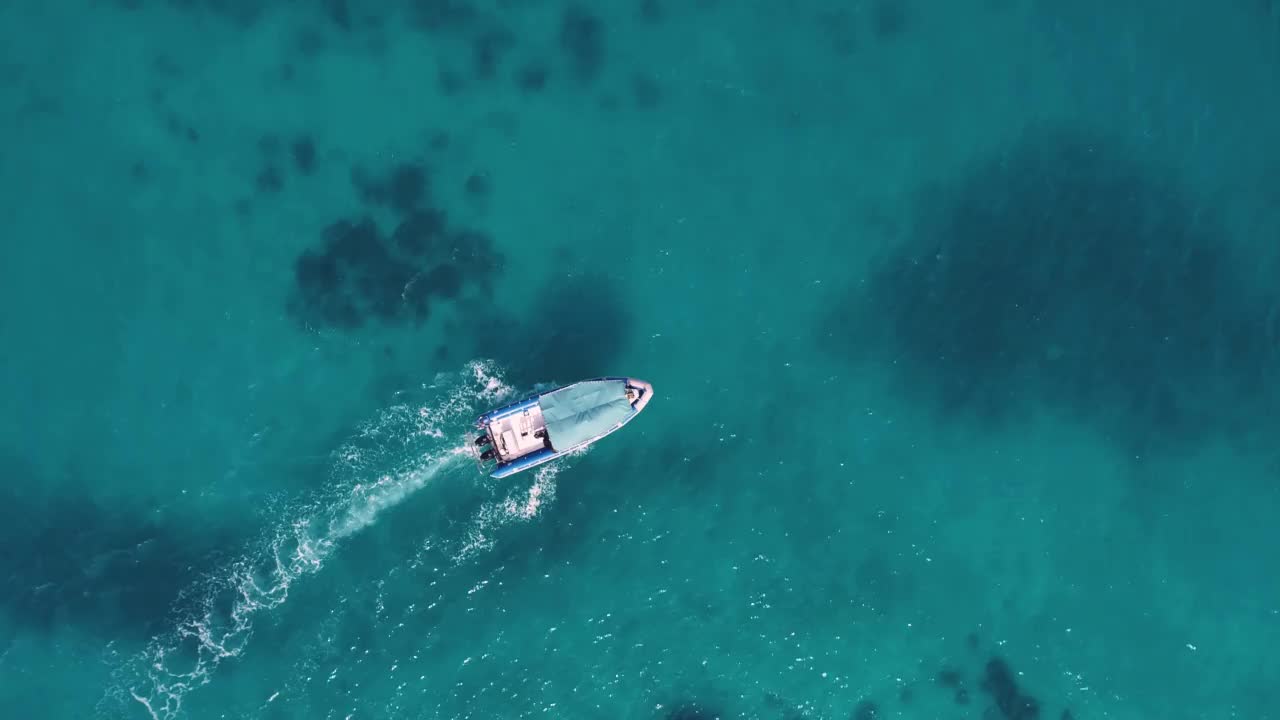 夏日阳光明媚，渔船在湛蓝透明的水中的鸟瞰图。非洲桑给巴尔印度洋上漂浮船只的无人机俯视图。风景与游艇在清澈的大海视频素材