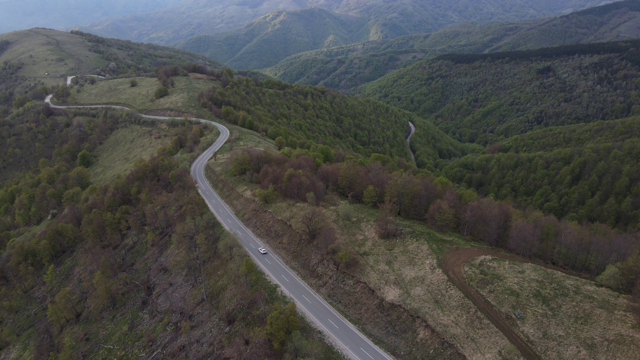 在道路上的俯瞰无人机跟随汽车，而驾驶旅游和旅游运输的概念，在秋天或冬天的一天，穿过田野和树木在塞尔维亚Knjazevac附近的老山stara planina视频素材