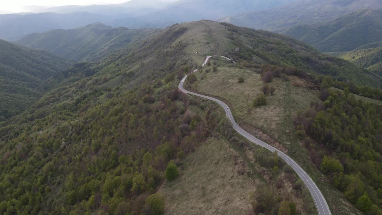 在道路上的俯瞰无人机跟随汽车，而驾驶旅游和旅游运输的概念，在秋天或冬天的一天，穿过田野和树木在塞尔维亚Knjazevac附近的老山stara planina视频素材