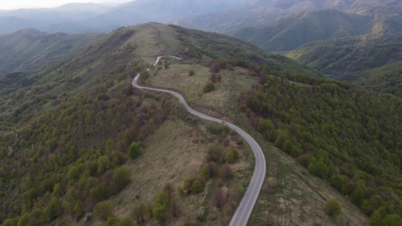 在道路上的俯瞰无人机跟随汽车，而驾驶旅游和旅游运输的概念，在秋天或冬天的一天，穿过田野和树木在塞尔维亚Knjazevac附近的老山stara planina视频素材