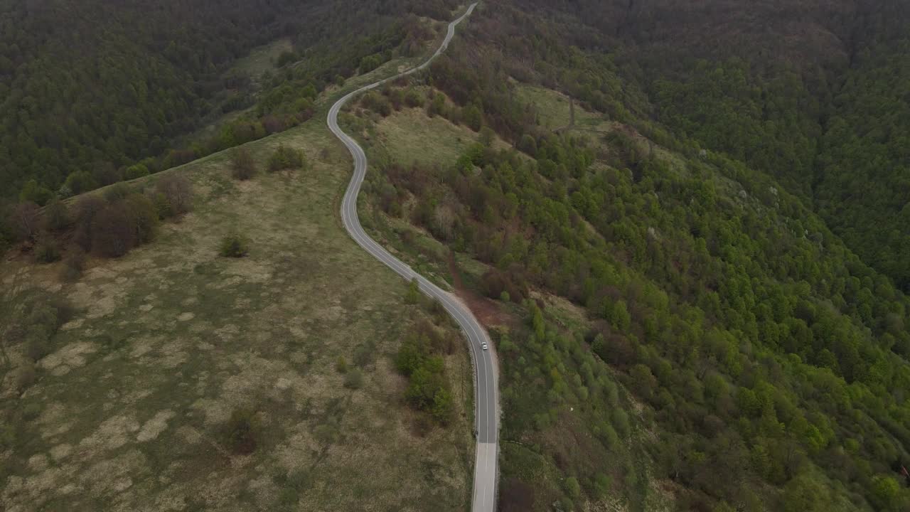 在道路上的俯瞰无人机跟随汽车，而驾驶旅游和旅游运输的概念，在秋天或冬天的一天，穿过田野和树木在塞尔维亚Knjazevac附近的老山stara planina视频素材