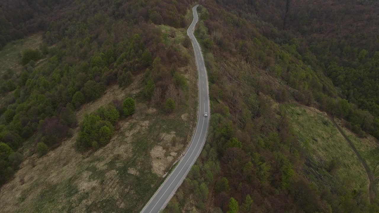 在道路上的俯瞰无人机跟随汽车，而驾驶旅游和旅游运输的概念，在秋天或冬天的一天，穿过田野和树木在塞尔维亚Knjazevac附近的老山stara planina视频素材