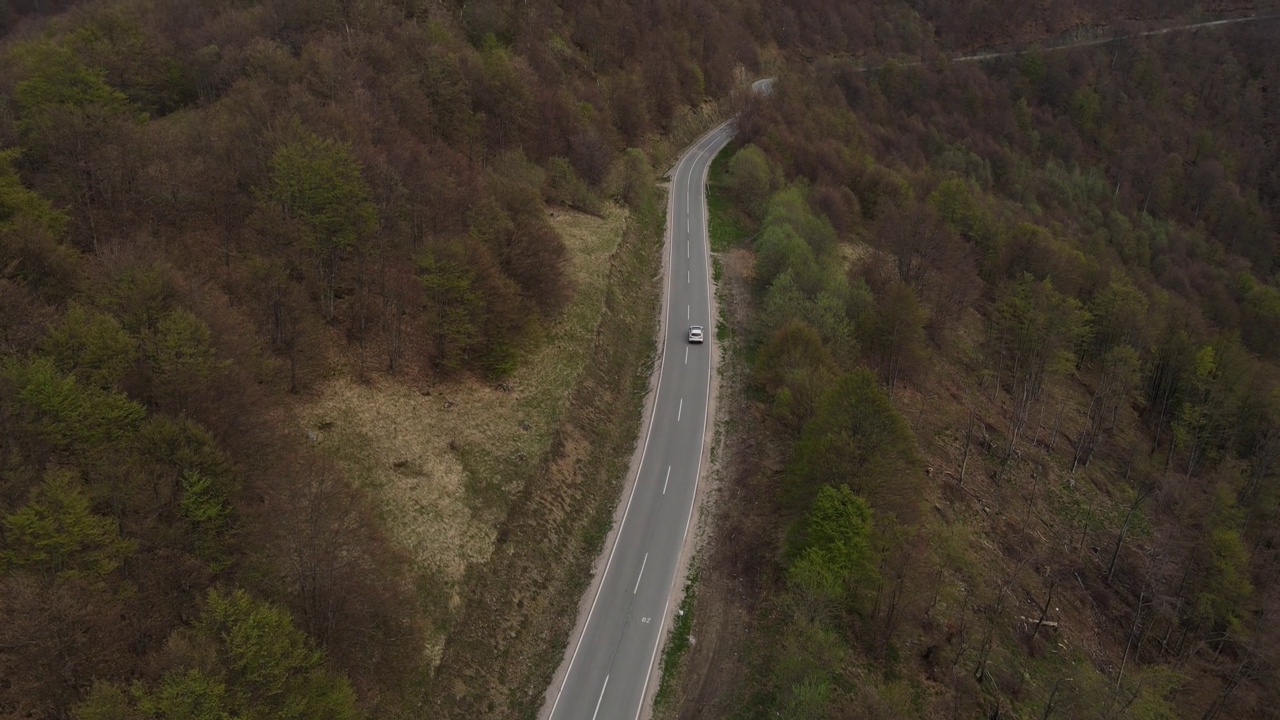 在道路上的俯瞰无人机跟随汽车，而驾驶旅游和旅游运输的概念，在秋天或冬天的一天，穿过田野和树木在塞尔维亚Knjazevac附近的老山stara planina视频素材