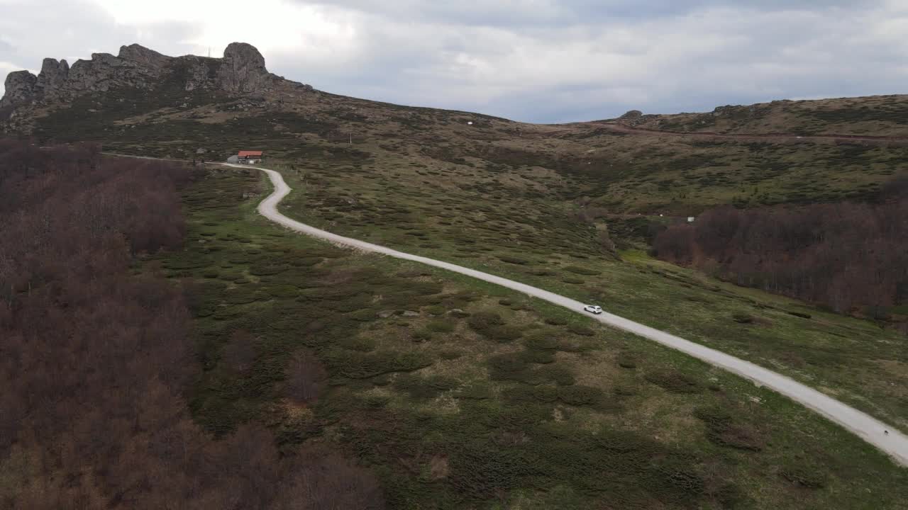 在道路上的俯瞰无人机跟随汽车，而驾驶旅游和旅游运输的概念，在秋天或冬天的一天，穿过田野和树木在塞尔维亚Knjazevac附近的老山stara planina视频素材