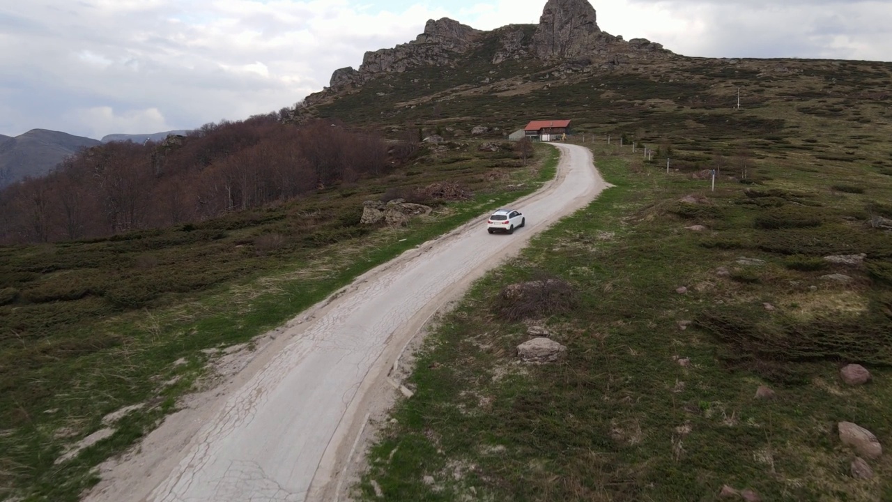 在道路上的俯瞰无人机跟随汽车，而驾驶旅游和旅游运输的概念，在秋天或冬天的一天，穿过田野和树木在塞尔维亚Knjazevac附近的老山stara planina视频素材