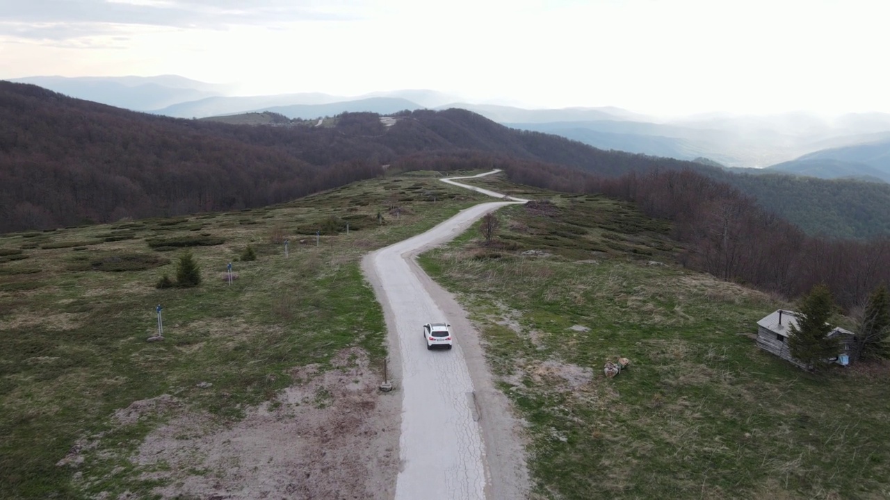 在道路上的俯瞰无人机跟随汽车，而驾驶旅游和旅游运输的概念，在秋天或冬天的一天，穿过田野和树木在塞尔维亚Knjazevac附近的老山stara planina视频素材