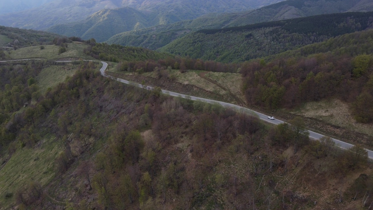 在道路上的俯瞰无人机跟随汽车，而驾驶旅游和旅游运输的概念，在秋天或冬天的一天，穿过田野和树木在塞尔维亚Knjazevac附近的老山stara planina视频素材