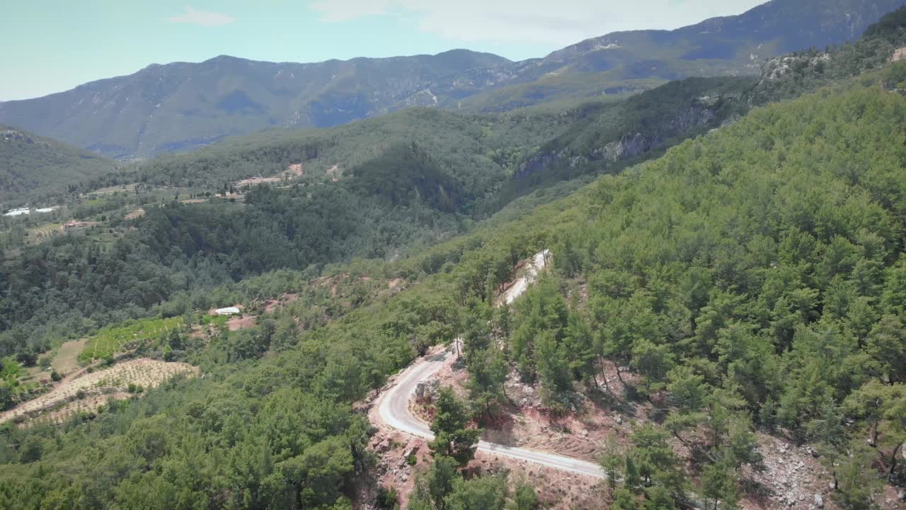 在晴朗的夏天，美丽的山峰映衬着清澈的蓝天。蜿蜒狭窄的汽车路穿过山峦和森林。旅游与旅游理念视频素材