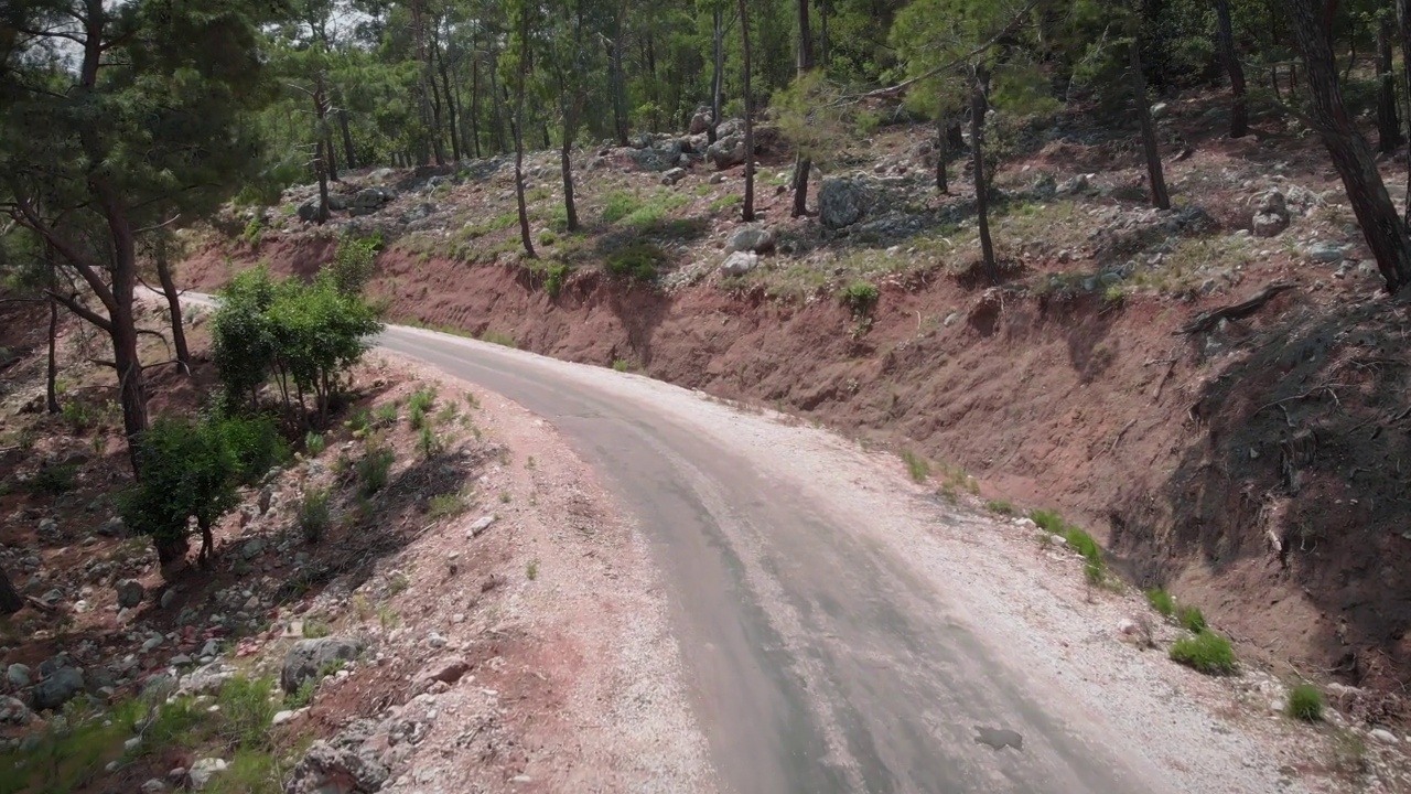 绿树林里蜿蜒狭窄的道路。空旷的汽车路穿过岩石峭壁和山坡上的石头。运输的概念。公路旅行度假。美丽的自然景观视频素材