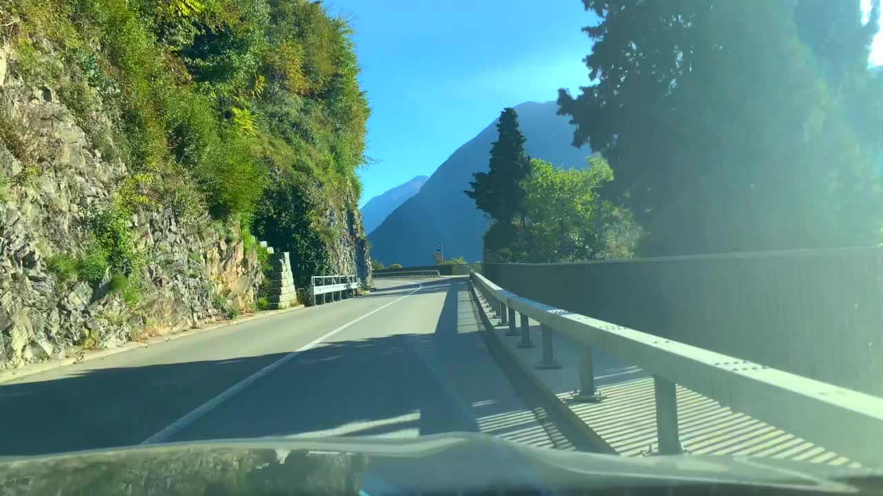 在甘达利亚的一个阳光明媚的日子里，在山路上与高山湖泊卢加诺的汽车观点视频素材