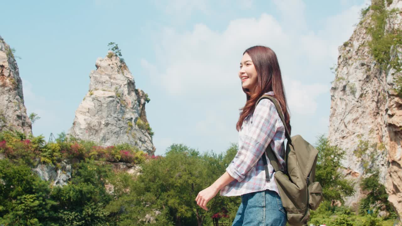 开朗的年轻旅行者与背包在山湖散步的亚洲女士。视频素材