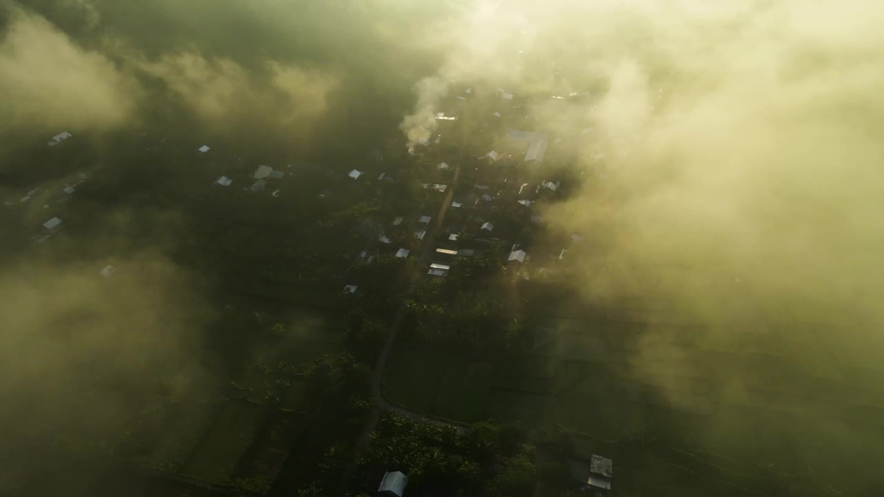 鸟瞰图，一个村庄的稻田和山丘在早晨笼罩在薄雾中视频素材