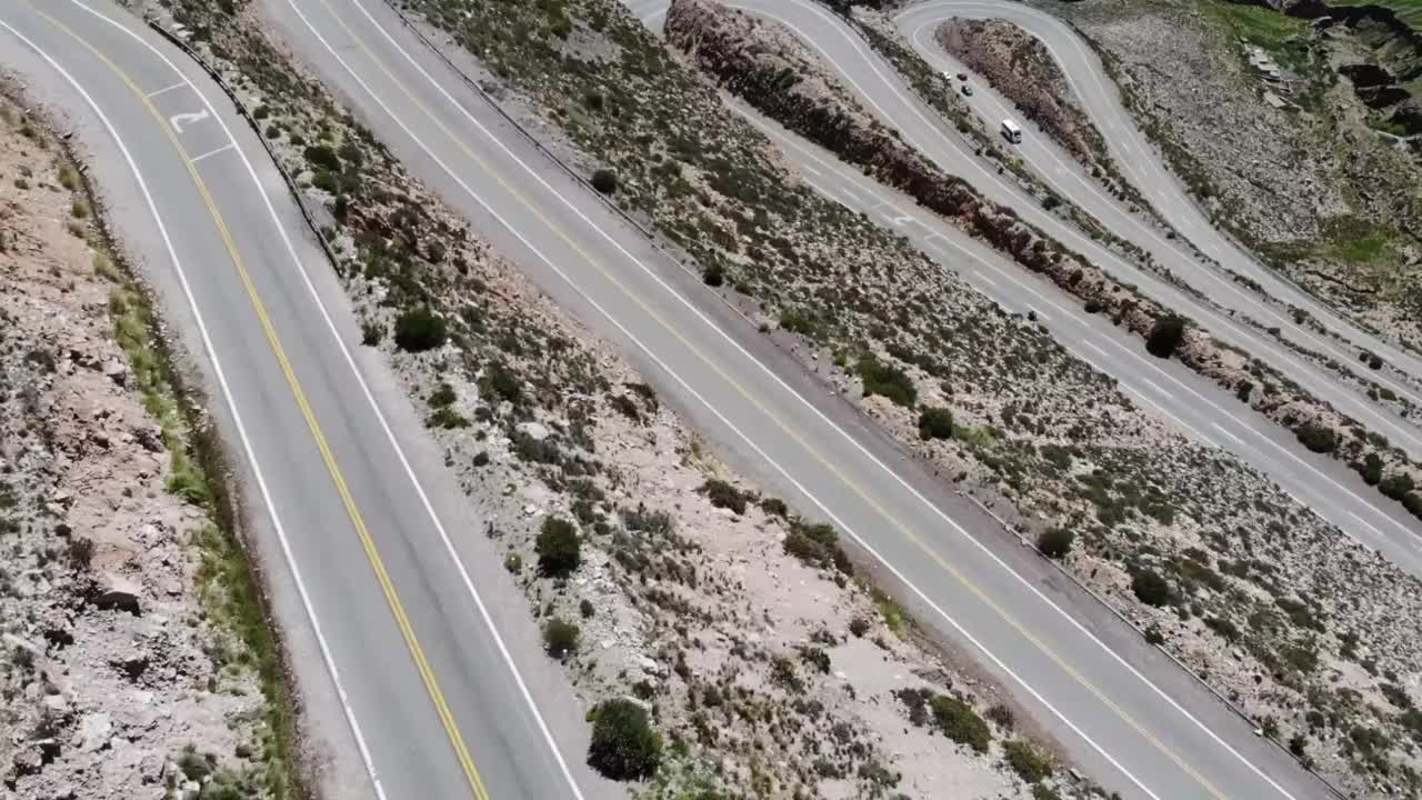 鸟瞰图蜿蜒的道路与几个发夹弯和驾驶汽车在山腰视频素材