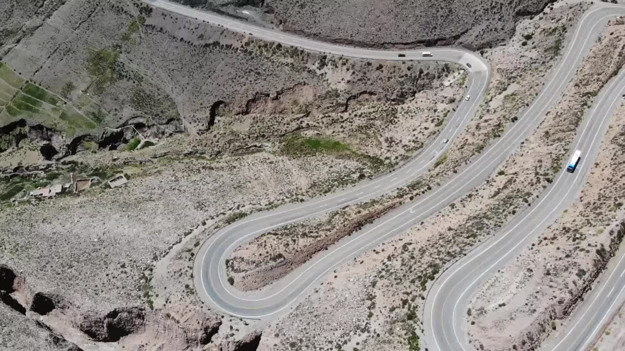 空中俯瞰的道路与几个发夹弯和驾驶车辆在山坡上视频素材