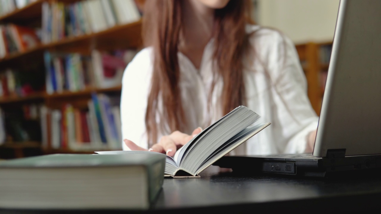 女学生在图书馆使用笔记本电脑进行在线教育。在线教育，电子教学的概念视频素材