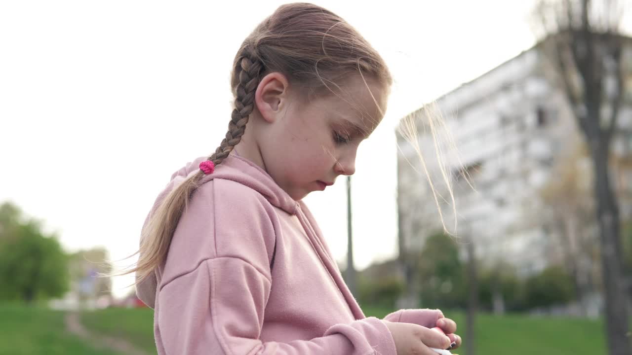 自然界的一个小女孩摄影师看着儿童相机上的镜头。视频素材