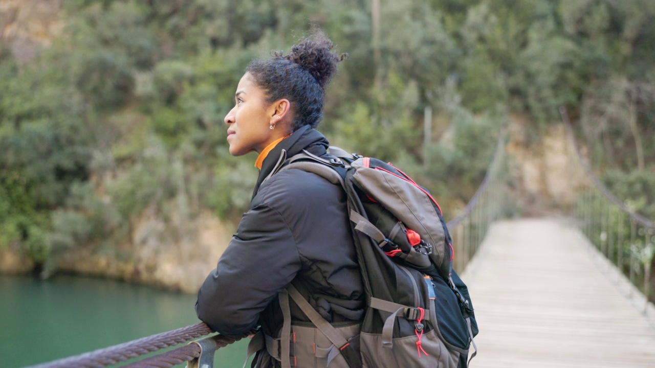 一个女人正在吊桥上徒步旅行。视频素材