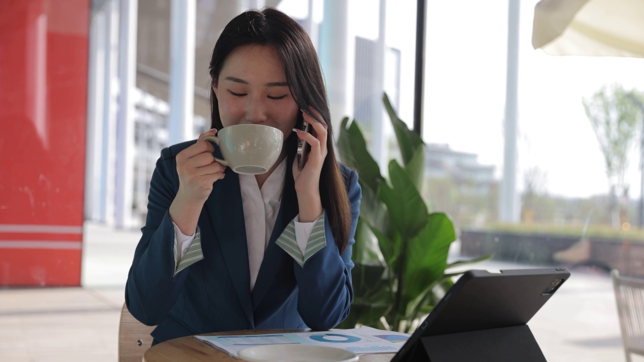 在咖啡馆喝咖啡的亚洲女商人一边用手机聊天视频素材