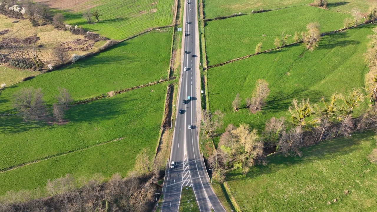 鸟瞰图之间的绿色农业领域与快速驾驶的汽车。从无人机俯瞰公路交通视频素材