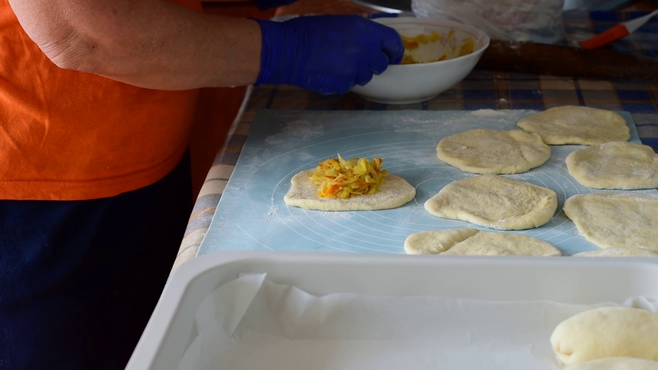 一个女人在做馅饼的面团里装满馅料。视频素材