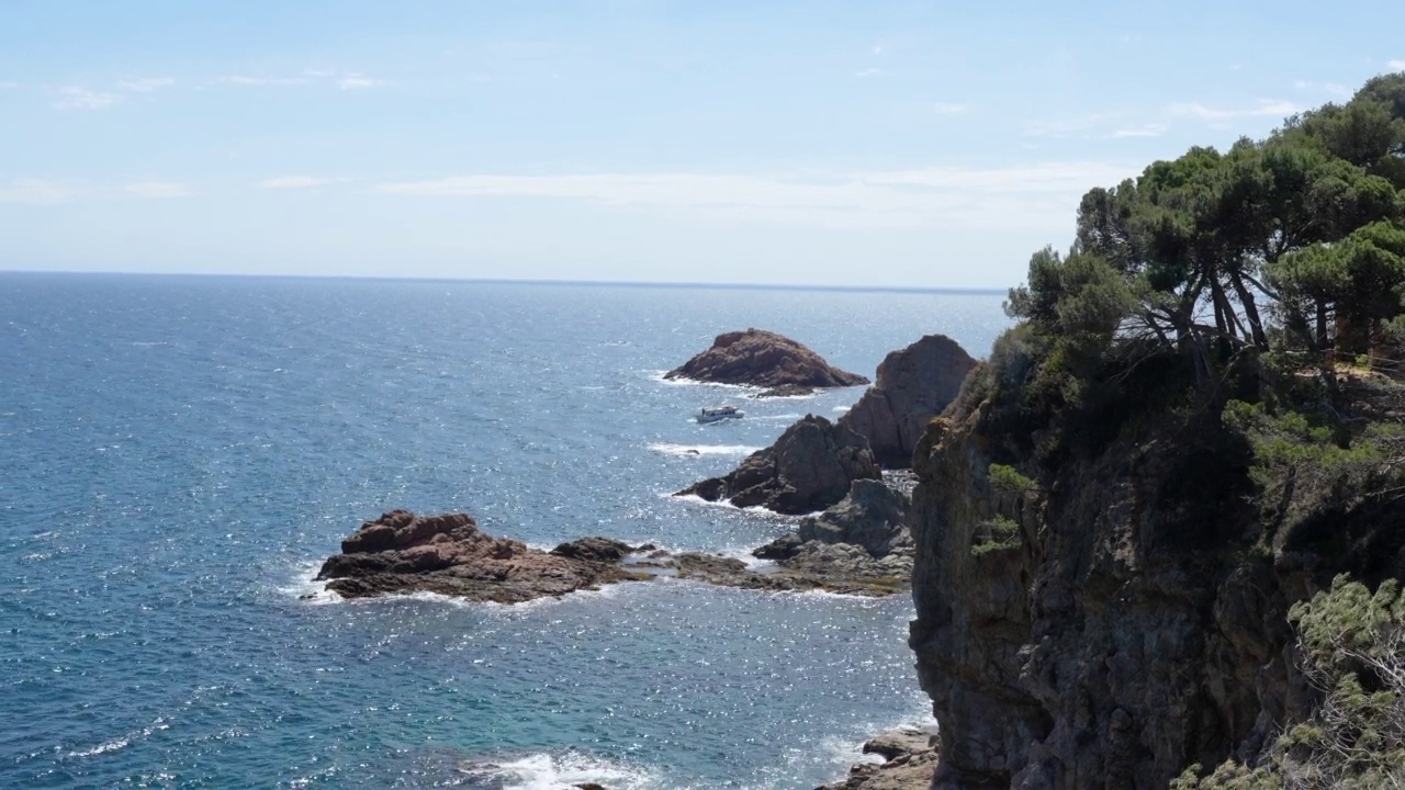 一艘白色小船与游客在地中海崎岖的岩石海岸附近的无人机视图。视频素材