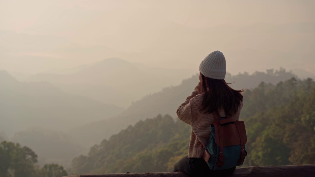 快乐的年轻女子旅行者放松和在山顶美丽的日出拍照视频素材