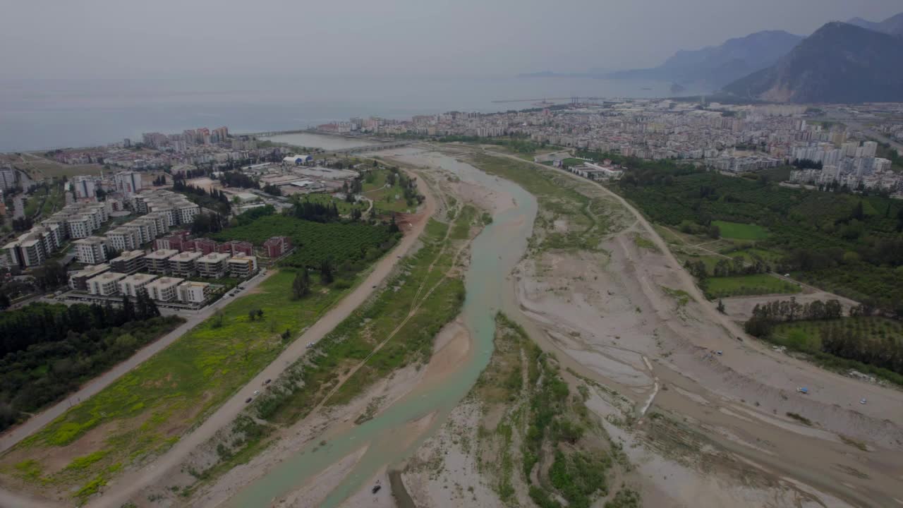 用无人机在河床上空飞行，观赏城市和山景。视频素材