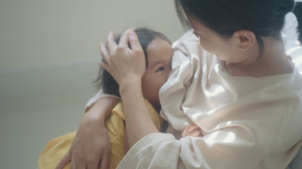 亚洲母亲积极的情感拥抱和哺育女儿，女儿抚摸母亲展现彼此的爱的家庭生活关系视频素材