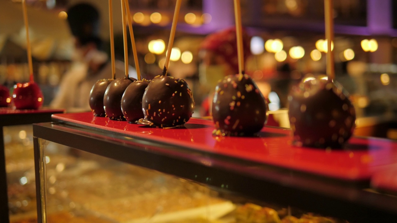 在酒店用巧克力装饰的手蘸焦糖苹果。视频素材