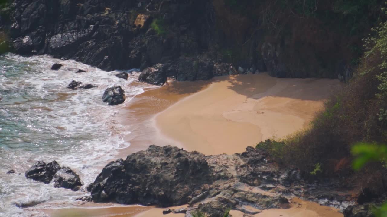 慢动作拍摄强烈的海浪撞击海岸和岩石在Kakolem海滩，从山上看到在印度果阿。暴风雨期间，强烈的海浪拍打着岩石。视频素材