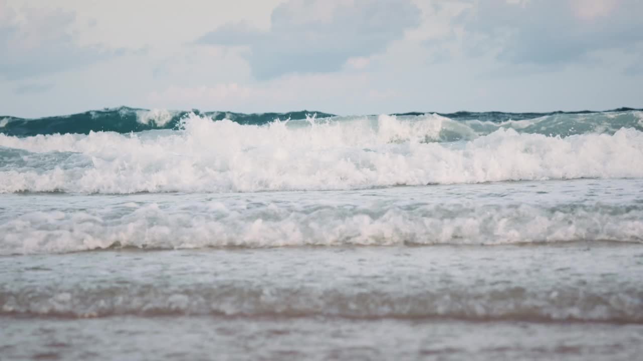 夏天的海滩、海沙和天空。海滩遇见深蓝色的海水和泡沫的波浪视频素材