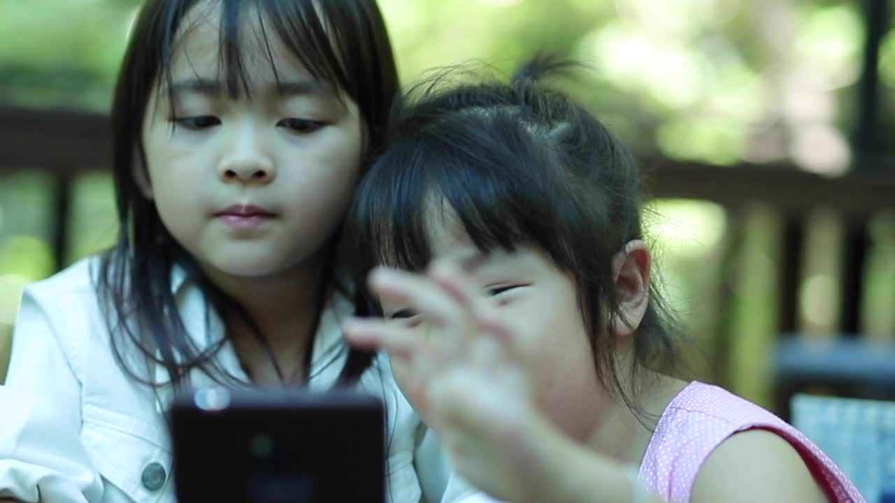 两个小女孩在看手机视频素材