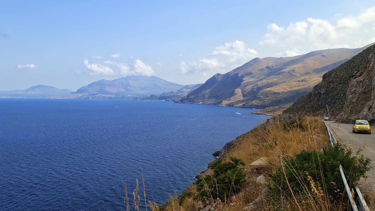 西西里岛Riserva dello Zingaro自然保护区的惊人全景全景，黄色汽车在沿海道路上。意大利视频素材