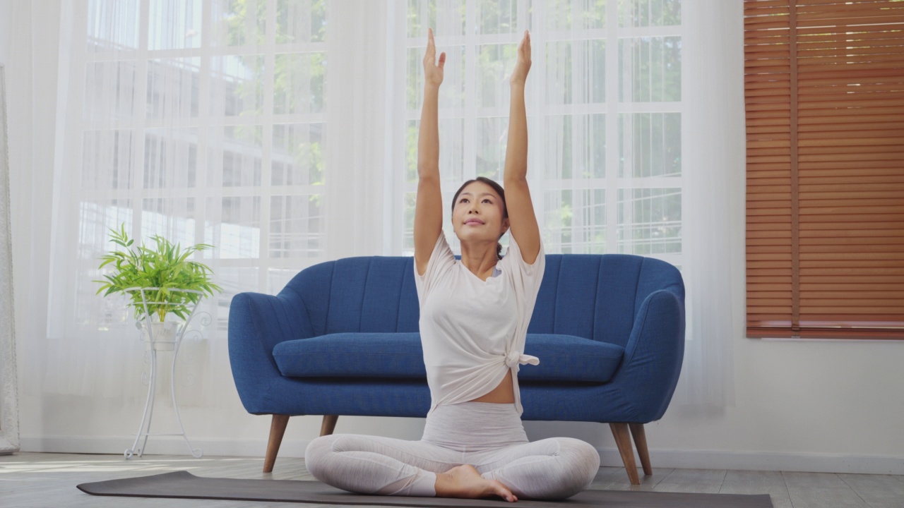 女性在家做伸展运动，坐在垫子上的侧角姿势，瑜伽锻炼。视频素材