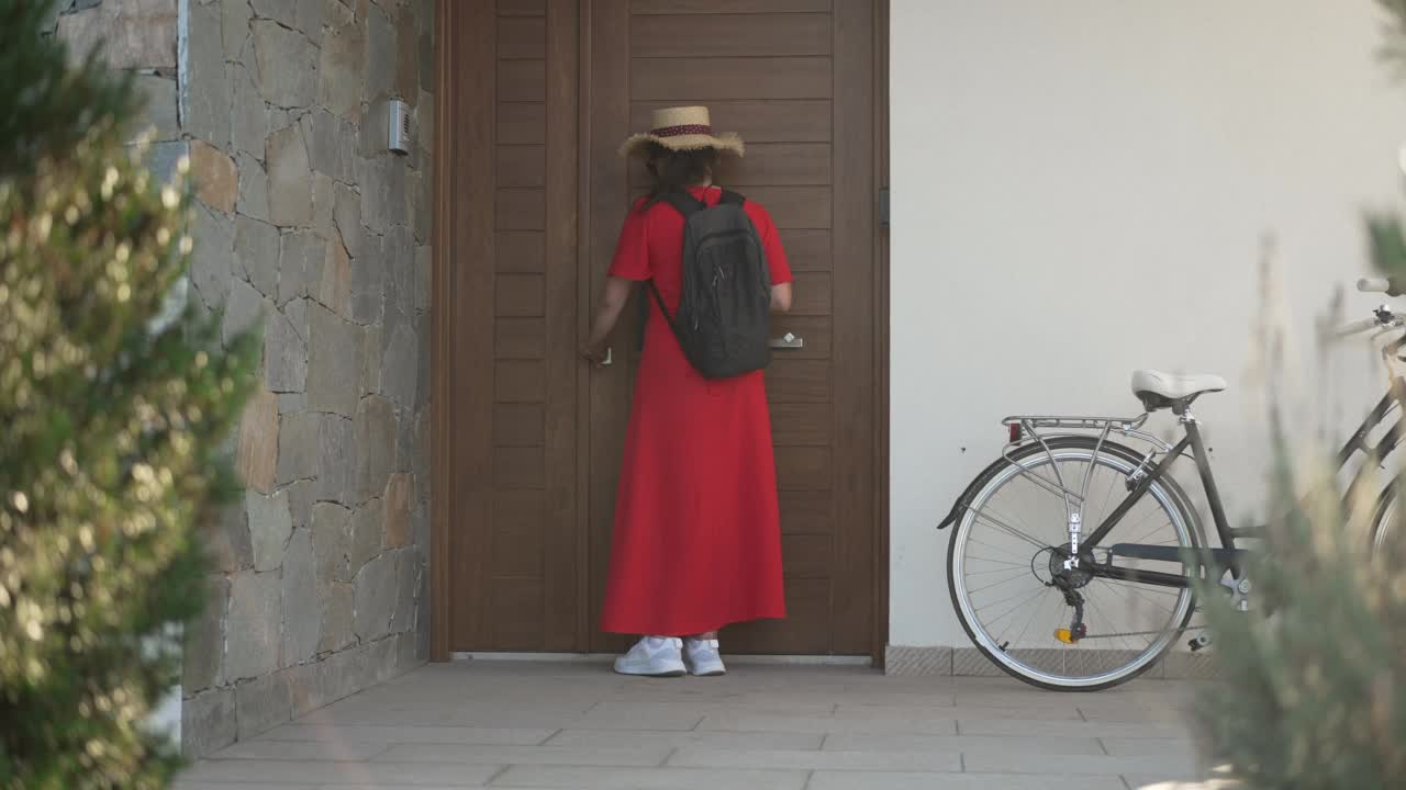 广角镜头，年轻女子锁门离开，自行车在外面。积极的白人女性骑自行车步行与自行车在慢动作。健康的生活方式和自信的概念。视频素材