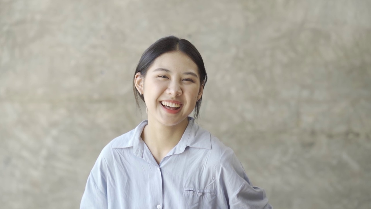 可爱的年轻亚洲女人微笑的慢动作在相机近距离一个美丽的亚洲女人微笑在相机室内。视频素材