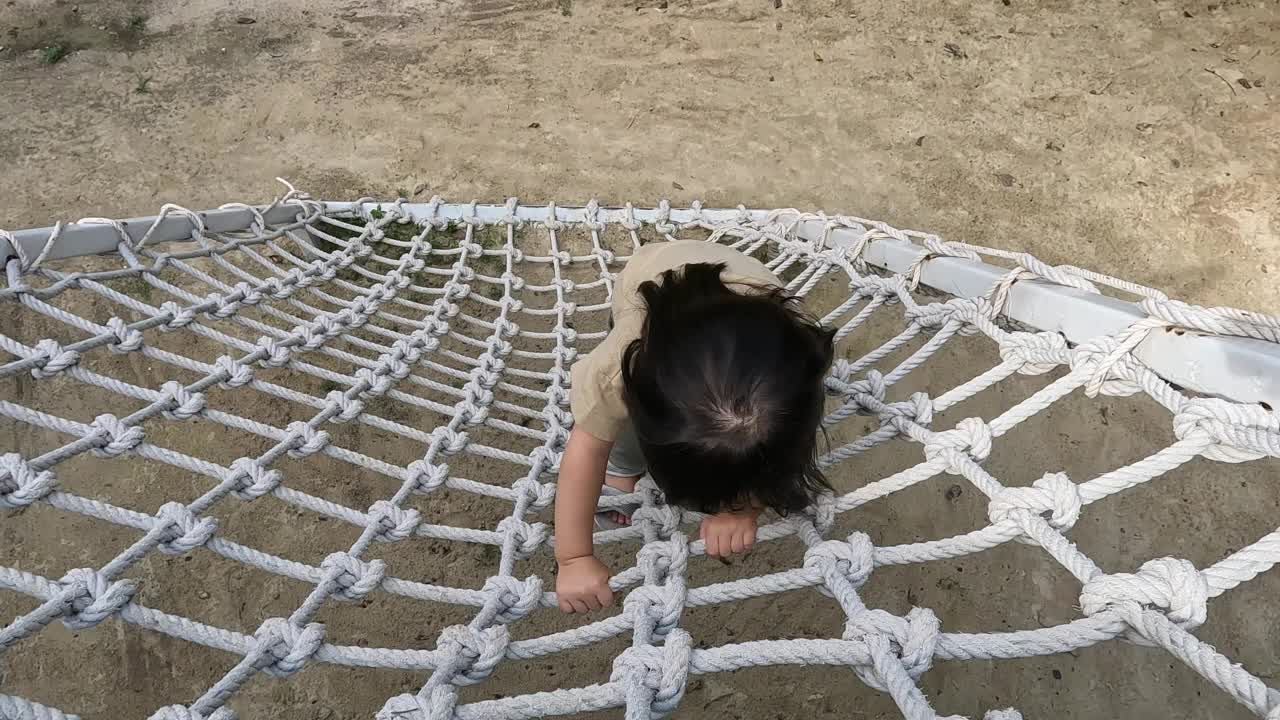 一个女孩在操场上爬绳子视频素材