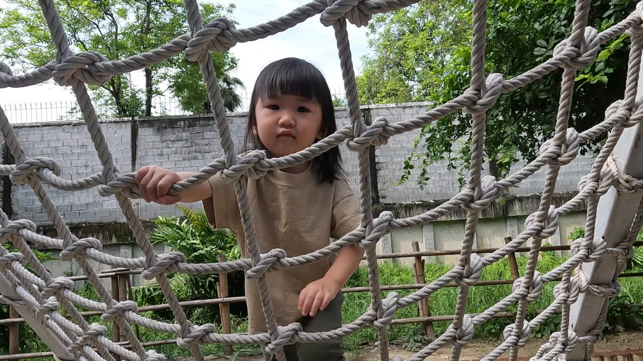 一个女孩在操场上爬绳子视频素材