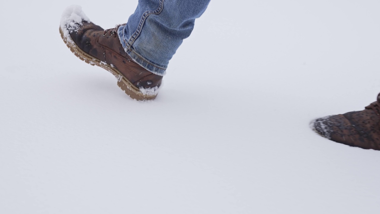 男人的脚在雪地上行走视频素材