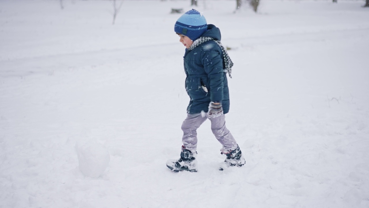 小男孩在为雪人打雪仗视频素材