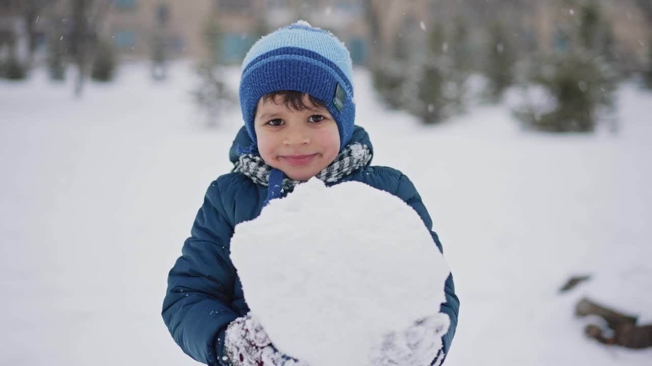 男孩拿着一个大雪球视频素材