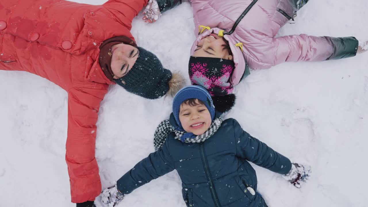 孩子们躺在雪地上做雪天使视频素材