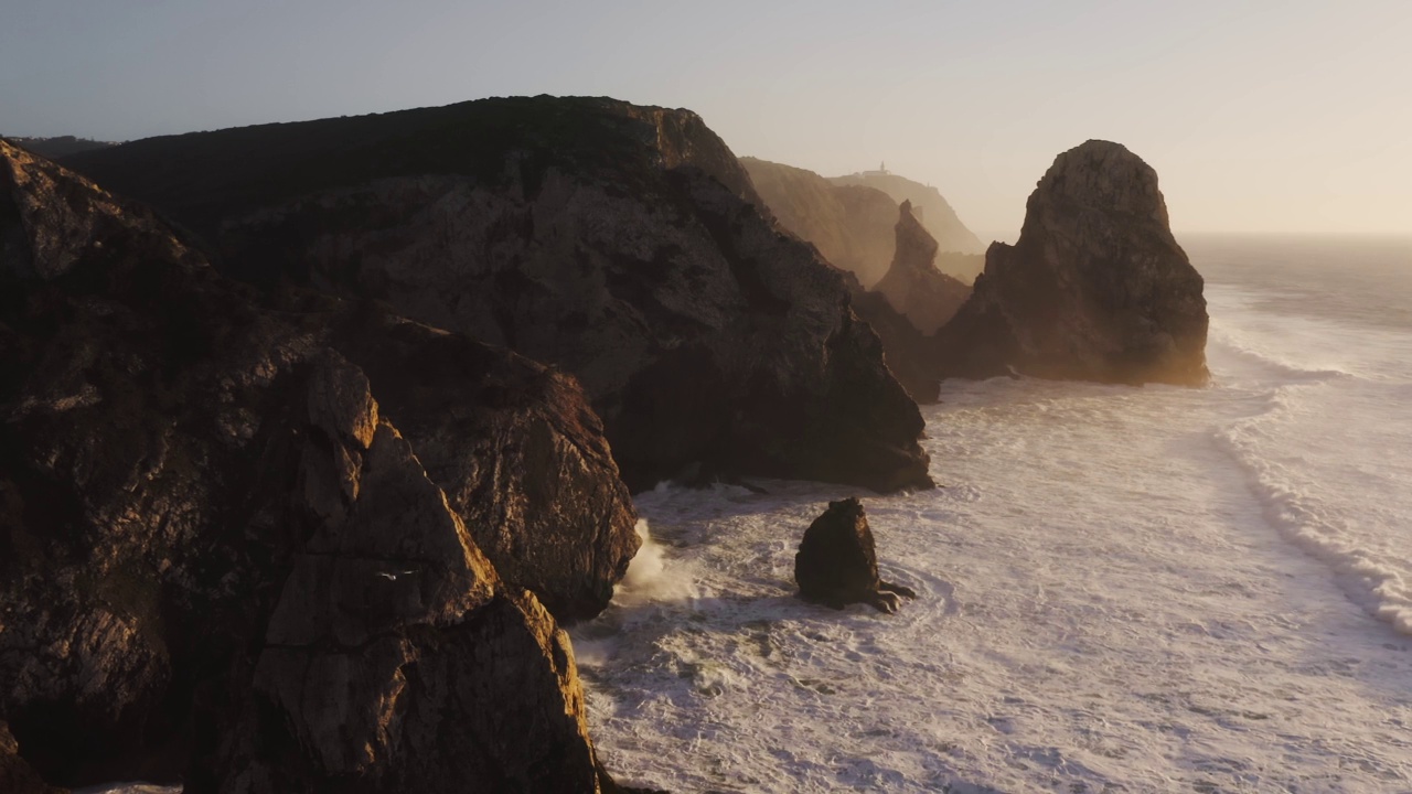 在里斯本的悬崖和戏剧性的葡萄牙海岸风景的无人机视图，大西洋和海岸岩石形成的景观，岩石和岩石海岸线，欧洲与橙色的夕阳视频素材