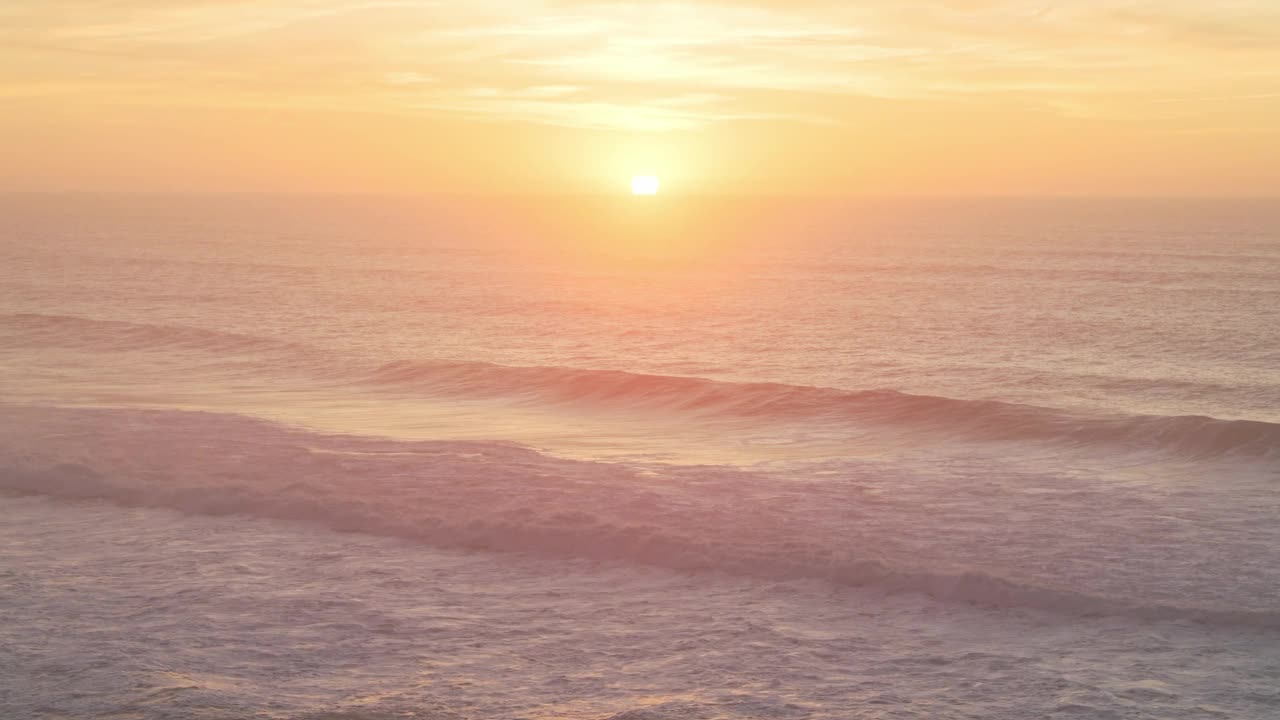 美丽的波浪打破海洋海景背景在日落与日落，柔和的温暖的橙色颜色从高空无人机的看法视频素材