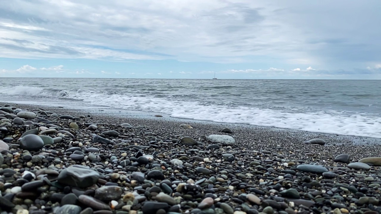 海浪在沙滩上低角度观景。海面上的阴沉天空。视频素材