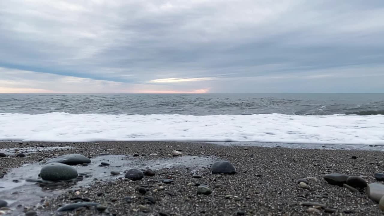 海浪在沙滩上低角度观景。海面上的阴沉天空。视频素材