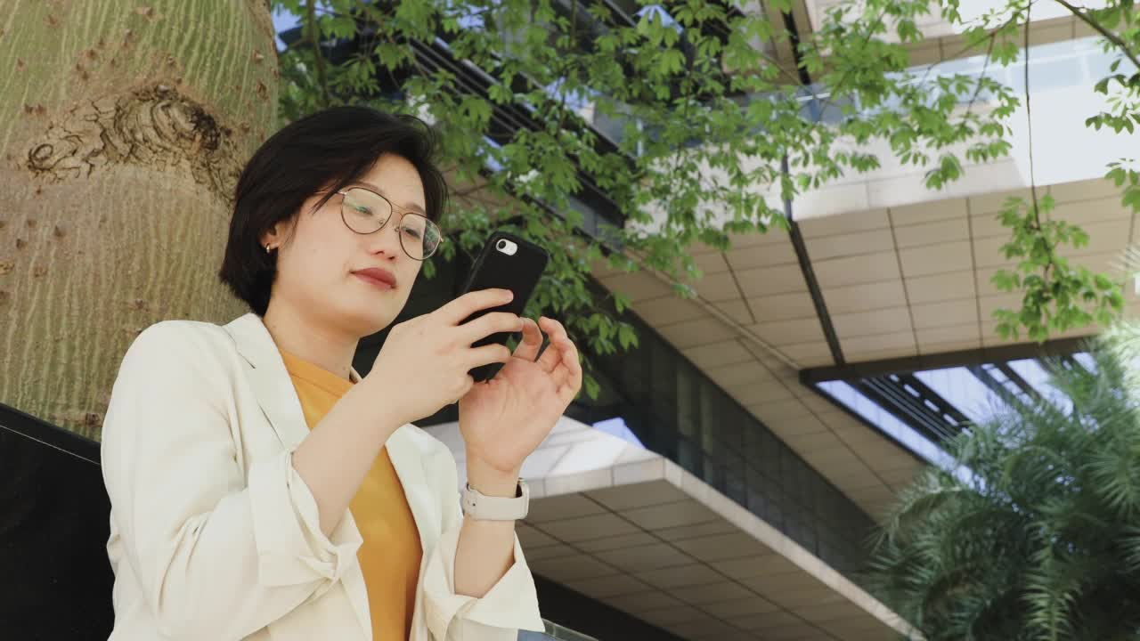 亚洲女性在城市户外使用手机视频素材