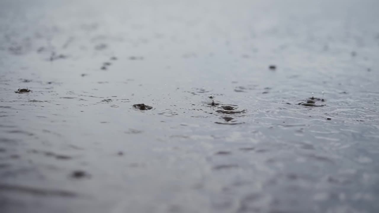 雨滴经常滴在水面上，水花飞溅可见，特写镜头。视频素材