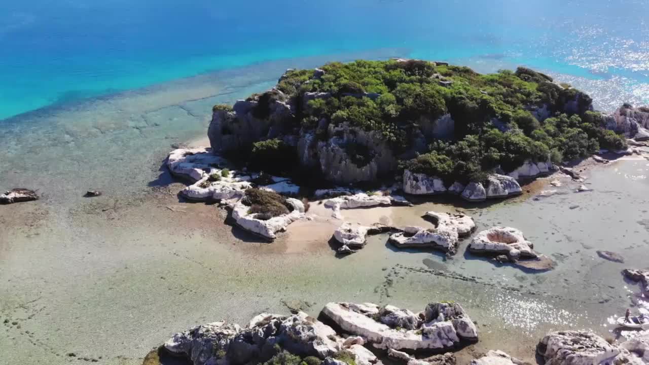 阳光明媚的日子里，蓝色的大海、浅浅的海水和美丽的岩石的鸟瞰图视频素材